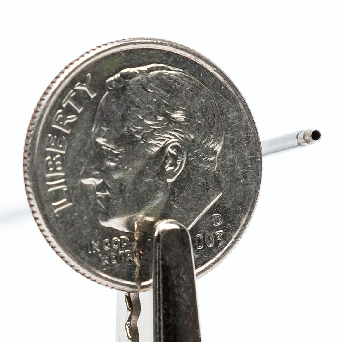 Small bore, double walled, stainless steel, vacuum insulated sleeve compared to the size of a U.S. dime