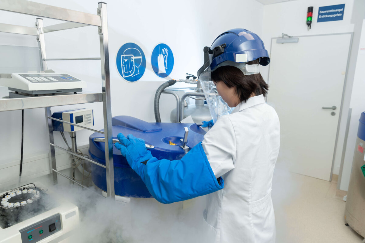 Medical researcher removes frozen cell cultures from a liquid nitrogen storage tank